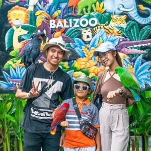 Anak-anak berinteraksi langsung memberi makan gajah di kebun binatang Bali yang asri.